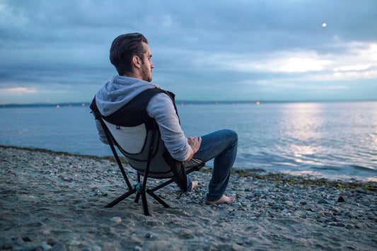 Man watching stormy sunset from beach sitting in cliq chair